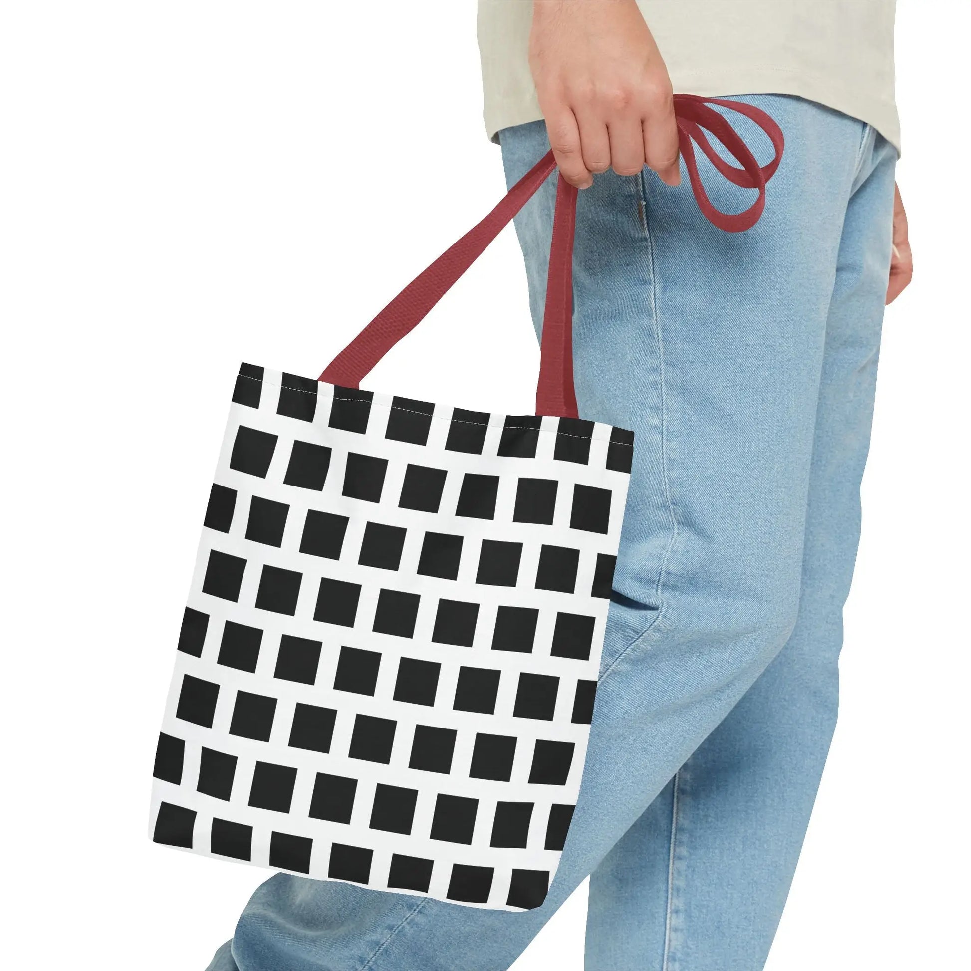 Black square pattern canvas tote bag with white geometric design and red fabric handles for versatile use