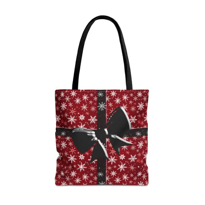 Red holiday tote bag with black handles and festive black bow design on reusable eco-friendly fabric with snowflakes background