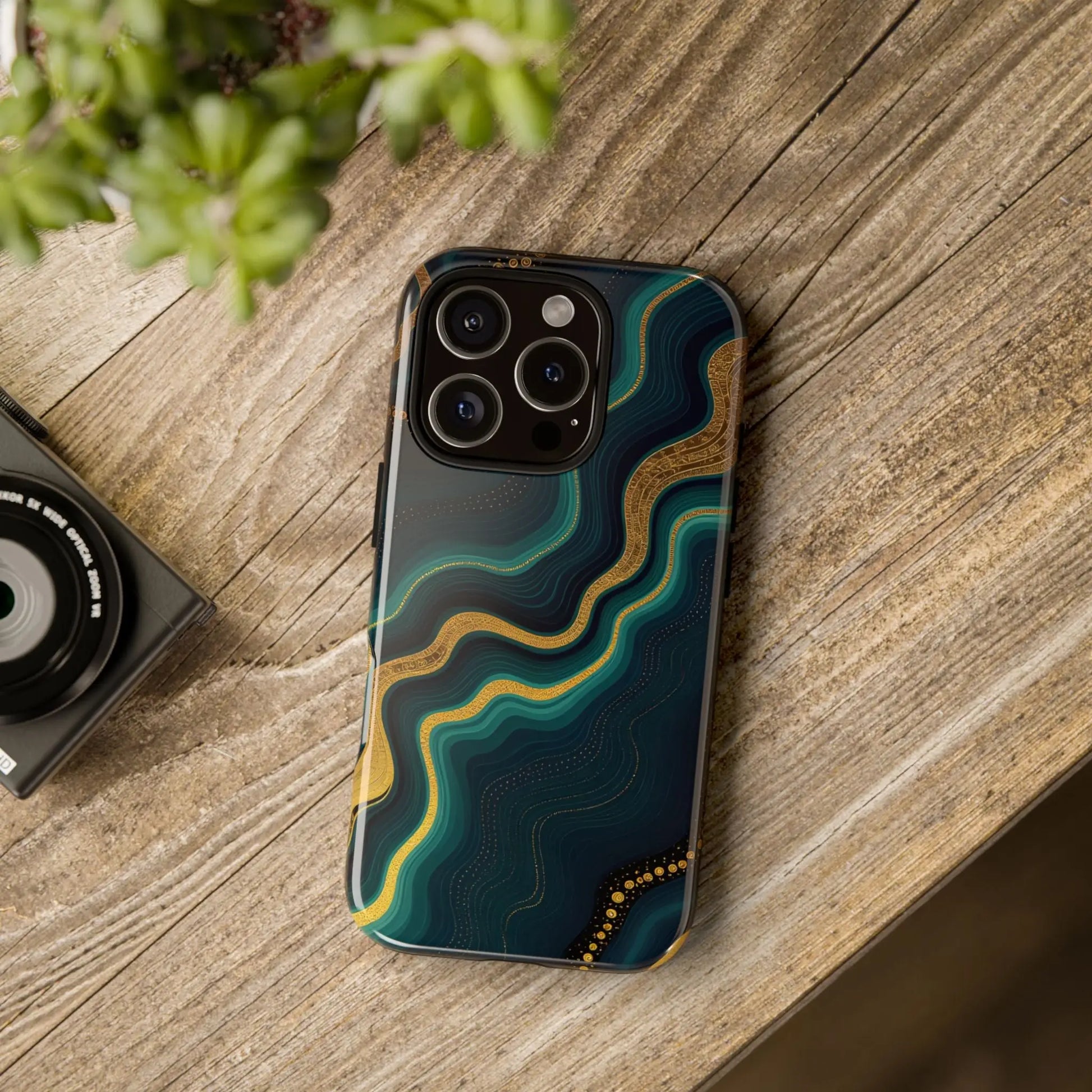 Back of a sleek elegant geode phone protector with deep teal and gold abstract wave design and subtle dot accents