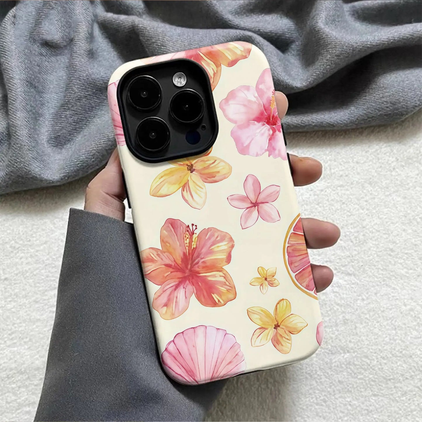 Back side of a flower phone case cover for iphone with pink orange and yellow hibiscus flowers on a cream background
