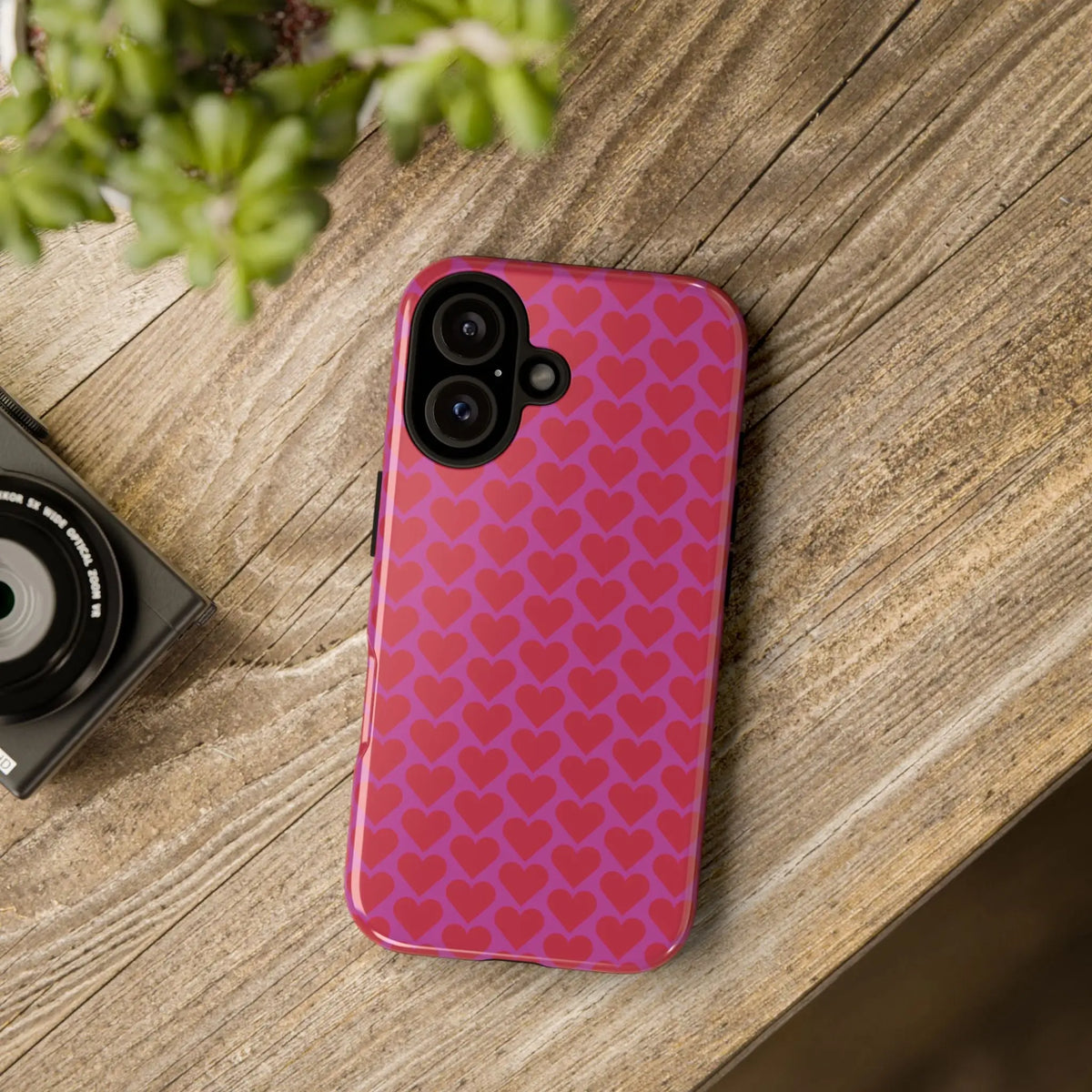 Back side of a vibrant pink heart pattern tough phone case with red hearts glossy finish and camera cutouts