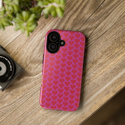 Back side of a vibrant pink heart pattern tough phone case with red hearts glossy finish and camera cutouts