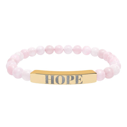 A delicate pink rose quartz natural stone stretch bracelet with a gold-toned hope engraved natural bar