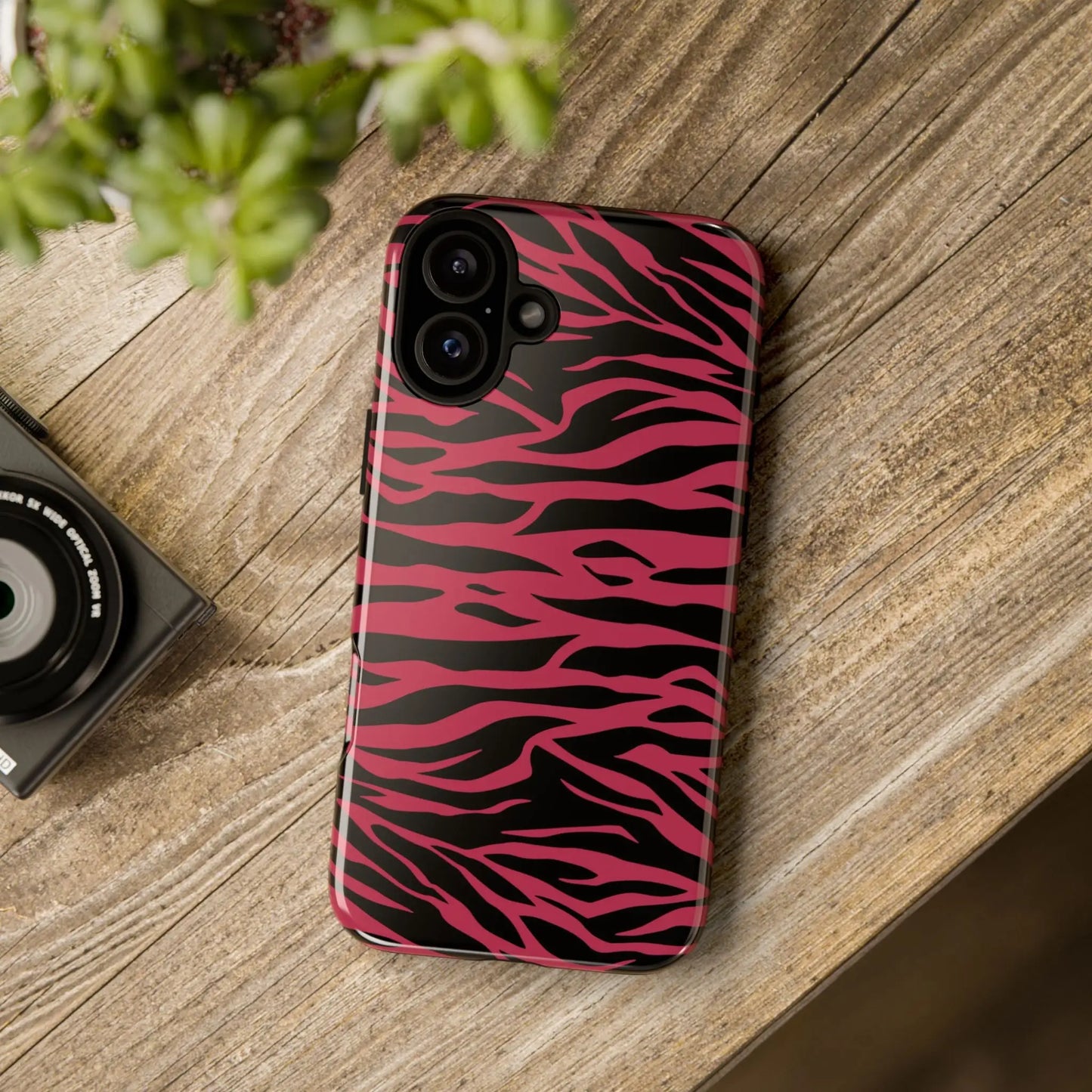 Back of a vibrant pink and black iphone 14 plus phone case with a glossy magenta wild tiger pattern print design