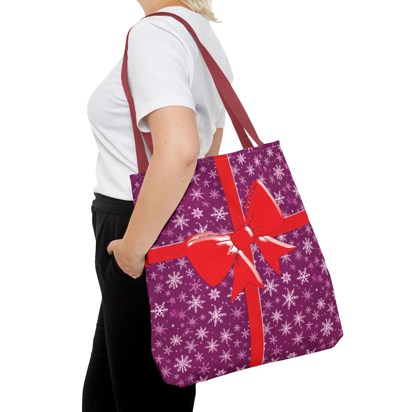 Pink christmas tote bag with purple snowflake pattern and red bow design, featuring black white and red handles