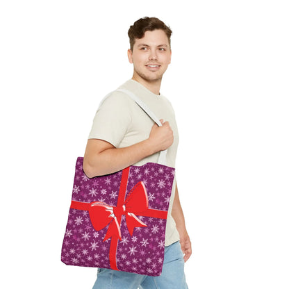 Pink christmas tote bag with purple gift wrap design, red bow, white snowflakes, and red handles for festive shopping
