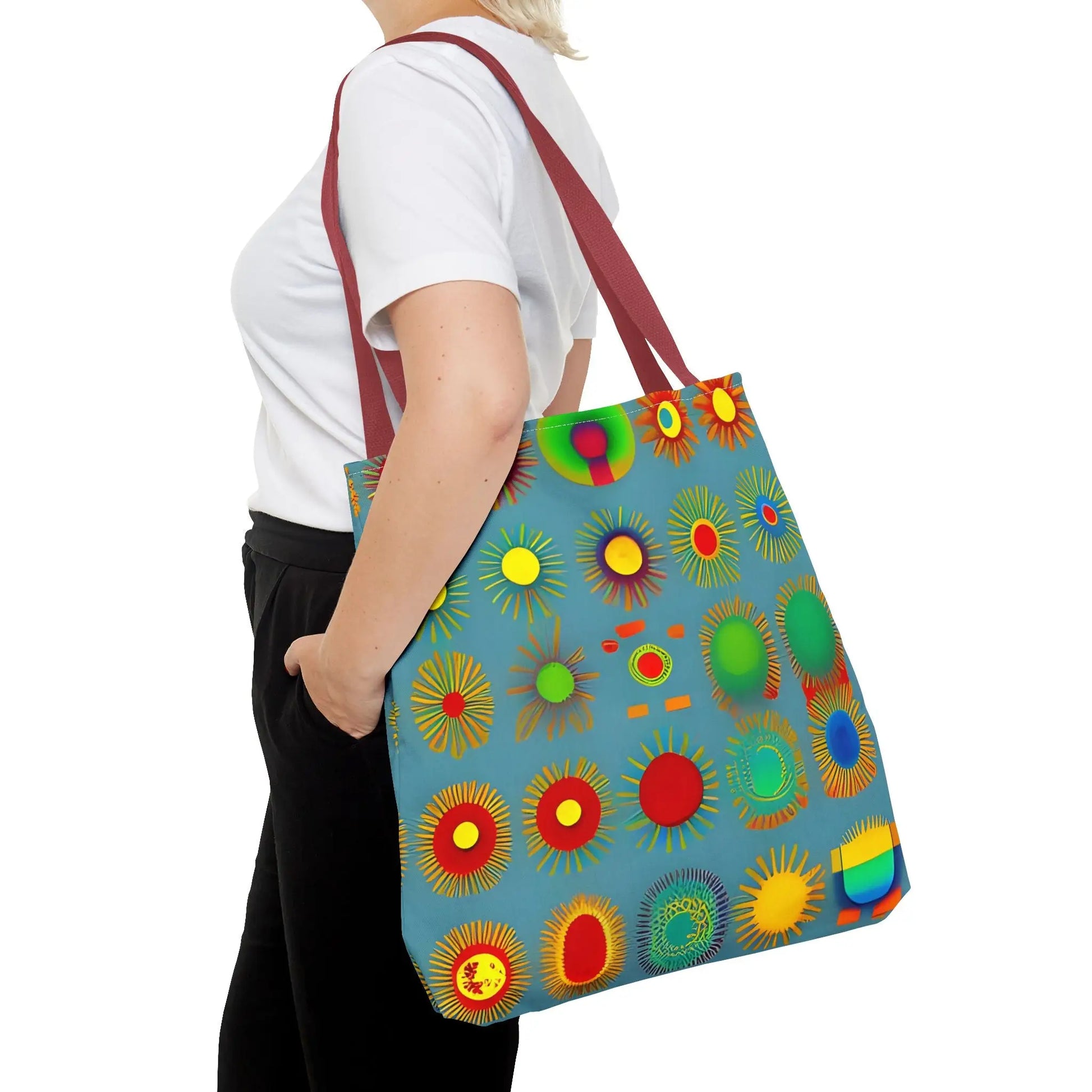 A vibrant blue sun pattern tote bag with colorful sunburst circles and contrasting maroon straps